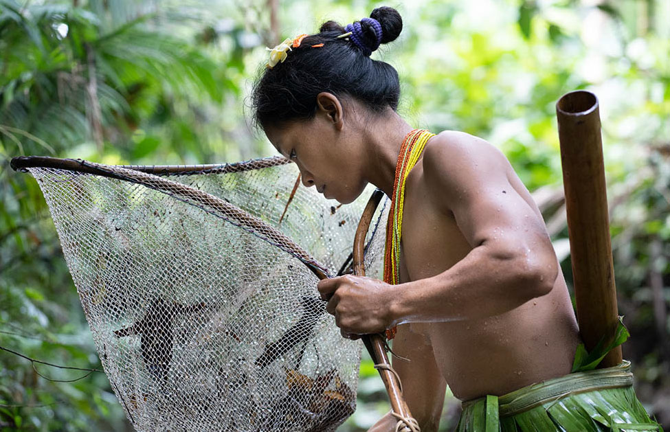 Bai Tiru, a Mentawai mother fishes in the river for crabs, shrimp, and fish.