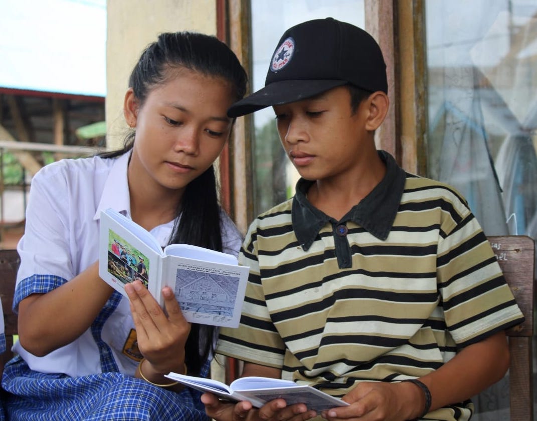 Indigenous Mentawai school student communicates with a young boy using the Mentawai language dictionary, published by @sukumentawai in 2019 